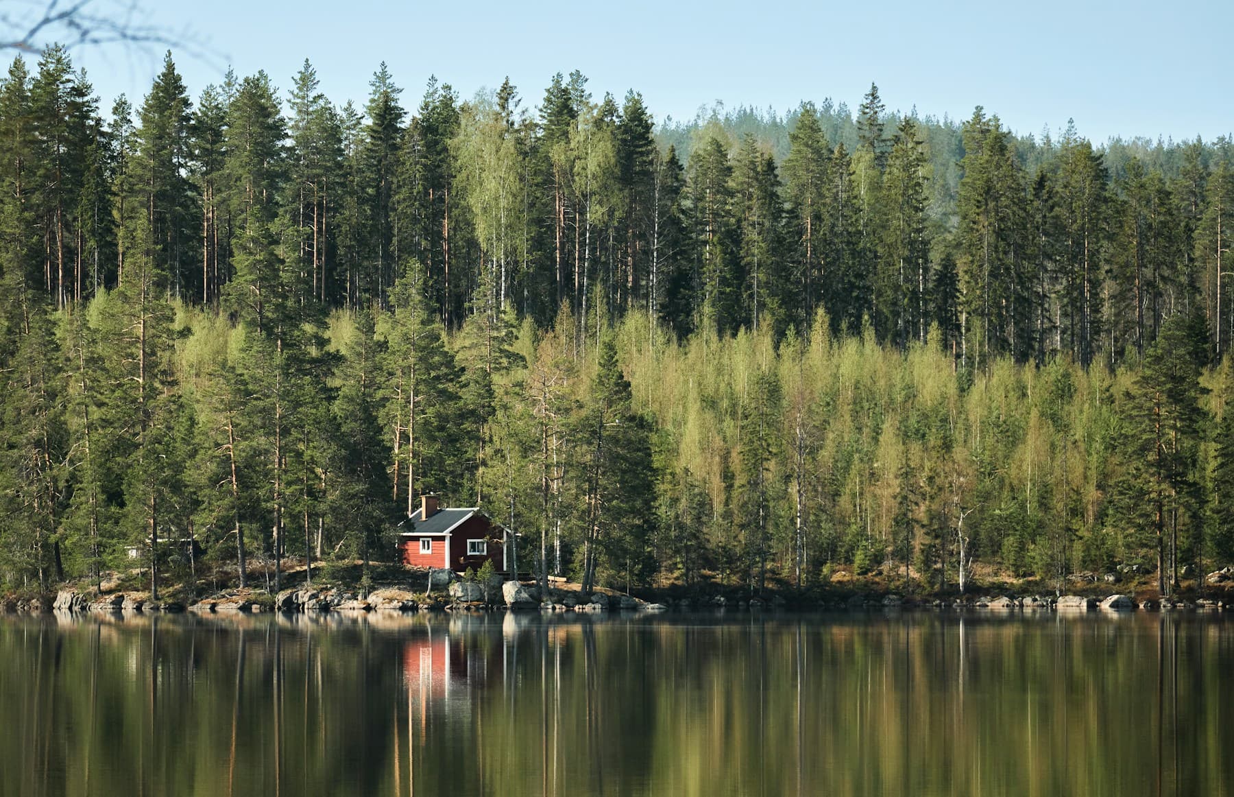 Rött fritidshus vid en stilla sjö i Dalarna