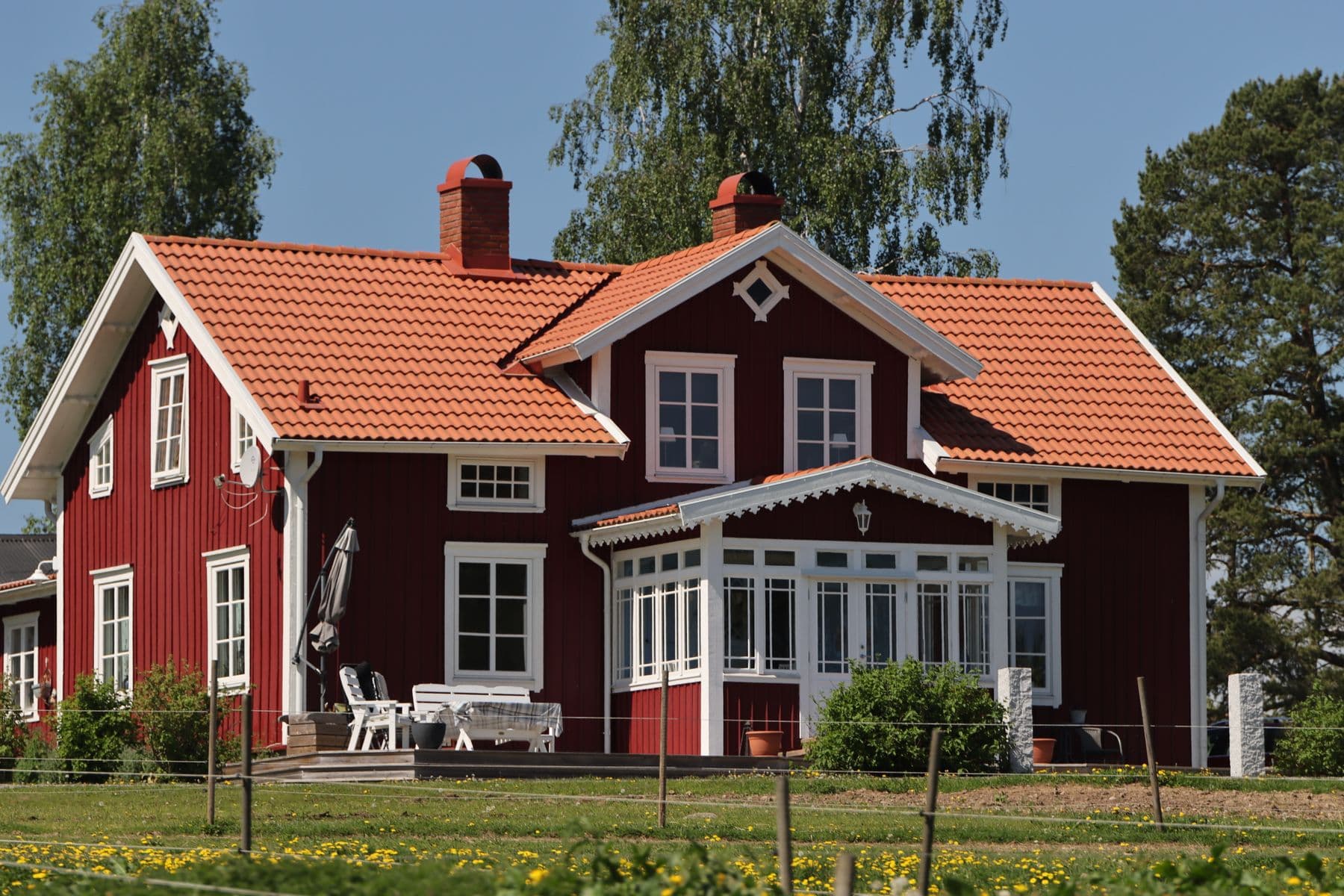 Röd svensk villa med vita knutar i sommarljus